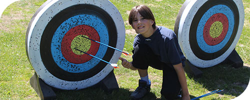 Child knealing in front of archery target 
